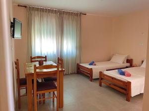 a room with two beds and a table and chairs at Chris Apartment in Ksamil