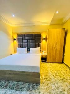 a bedroom with a large white bed and a wooden cabinet at Global Suites in Kano
