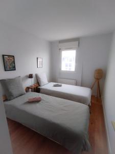 zwei Betten in einem kleinen Zimmer mit Fenster in der Unterkunft T3 en face de la gare, Terrasse-Rooftop, Parking in Houilles