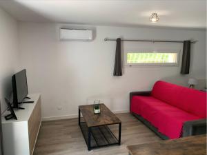 a living room with a red couch and a table at Le Grenadier in Saint-Mitre-les-Remparts