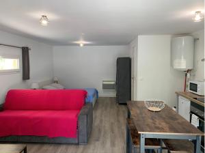 a living room with a red couch and a table at Le Grenadier in Saint-Mitre-les-Remparts