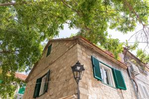 a building with green shuttered windows and a street light at La Perla - Downtown House in Omiš