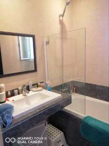 a bathroom with a sink and a mirror and a tub at Appartement Résidence balnéaire Dar Al bahr in Sidi Rahal
