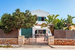 Una casa blanca con una mesa delante de ella. en Villa Jultomas, en Cala'n Bosch
