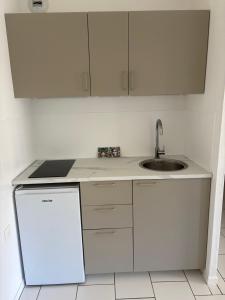 a white kitchen with a sink and a refrigerator at Casa Maxima - Cosy et Calme à 2 pas de la Mer in Sainte-Maxime