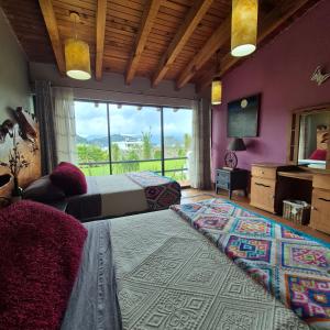 a bedroom with two beds and a large window at Casa Valle Horus in Valle de Bravo