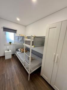 アルマカオ・デ・ペラにあるTomasoni summer houseの二段ベッド2台とキャビネットが備わる客室です。