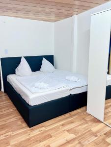 un letto con lenzuola e cuscini bianchi in una stanza di Messe Apartment in Laatzen mit kostenlosen Parkplätz ad Hannover