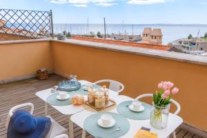 a table and chairs on a balcony with a view of the ocean at Portopiccolo Apartments in Sistiana