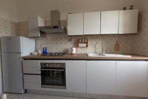 a kitchen with white cabinets and a white refrigerator at La Rotonda Fertilia apartment in Fertilia +22 photos
