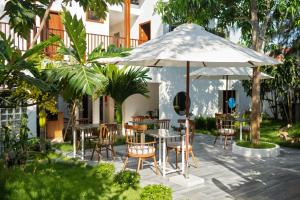 a patio with a table and chairs and an umbrella at Shoreline Stay in Hoi An