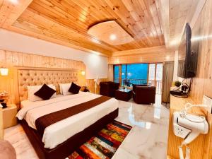 una camera da letto con un letto grande con soffitto in legno di Hotel Himalayan Valley View Retreat - Best Selling Riverside Hotel in Manali a Manāli