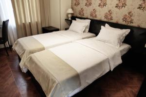1 dormitorio con 1 cama grande con sábanas y almohadas blancas en Hotel Four Brothers en Tiflis