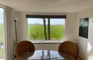 a dining room table with two chairs and a window at Chalet de Sudhoek in Vrouwenparochie +9 photos