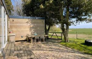 a patio with a table and chairs and a tree at Chalet de Sudhoek in Vrouwenparochie