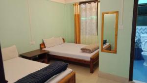 a small room with two beds and a mirror at Cozy Inn in Cherrapunji +26 photos