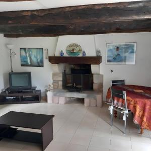 a living room with a fireplace and a television at Maison Le Clos Nalet in Matignon