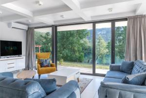 una sala de estar con muebles azules y una gran ventana. en Villa Una Residence, en Bihać