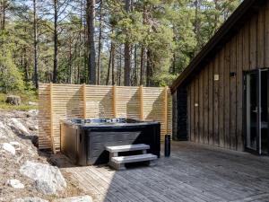 a hot tub on a deck next to a wooden building at Holiday Home Lagunen Villa 1 by Interhome in Hudiksvall