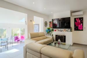 a white living room with a couch and a tv at La Maison Provençale in Mougins
