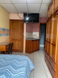 a room with a bed and a table and a kitchen at Hostal Abu Dhabi in Cuenca