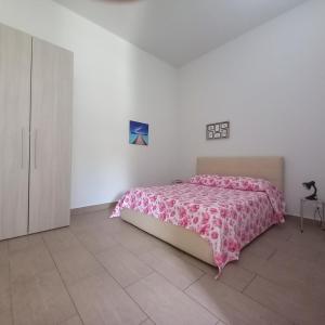 a bedroom with a pink bed in a white room at Dimore del Carrubo Villa Ovest in Marina dʼAvola
