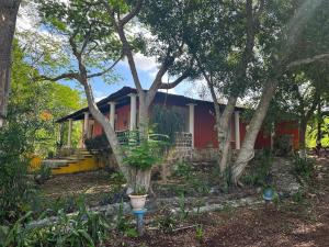 une maison rouge avec des arbres devant elle dans l'établissement Casa de campo Huerta De Calín, à Valladolid