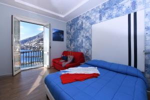 1 dormitorio con 1 cama azul y 1 silla roja en La Culla sul Mare centro storico, en Amalfi