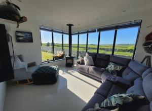 Country Cottage, Stunning Views في ترالي: غرفة معيشة مع أريكة زرقاء ونوافذ كبيرة