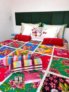 a bed with colorful blankets and pillows on it at Studio Chica Fulô - Village Capixaba in Gravatá