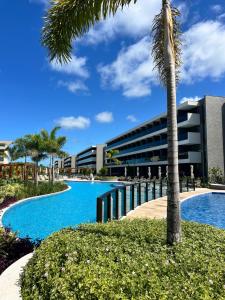 a palm tree in front of a building with a swimming pool at Beach Class Resort - Porto de Galinhas- Praia do Cupe in Porto De Galinhas
