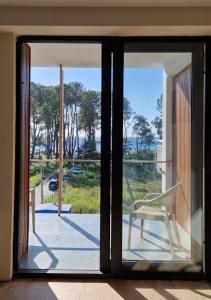 une porte en verre avec une chaise blanche sur un balcon dans l'établissement Terrace Kaprovan, à Shekvetili