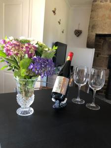 a bottle of wine and two glasses and a vase with flowers at The Stable in Sourdeval