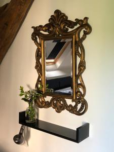 a mirror on a wall with a vase on a shelf at The Stable in Sourdeval