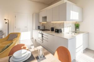 Una cocina con gabinetes blancos y una mesa y sillas. en Elegant Escape Eastbourne, en Eastbourne