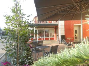 a patio with a table and chairs and an umbrella at Hôtel Terminus in Porrentruy