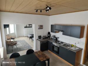a kitchen with black appliances and a living room at Fewo Monteurwohnung SAW in Salzwedel