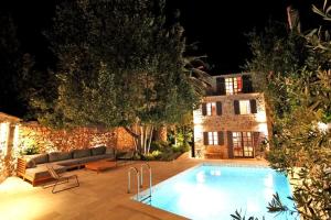 a swimming pool in front of a house at night at Villa Kuk in Bol