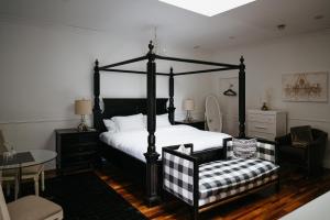 BloomfieldThe Bloomfield Inn的一间卧室配有一张黑色天蓬床和一把椅子
