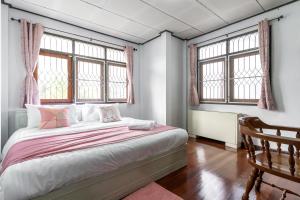 a bedroom with a bed and two windows at 110 House 4Bedroom in Ban Zong Katiam