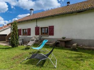 two chairs sitting in the grass in front of a house at Gîte paisible dans ancienne ferme comtoise avec animaux acceptés - FR-1-583-416 in Saint-Bresson