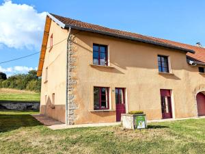 ein Haus mit roten Türen und einem Rasenplatz in der Unterkunft Maison spacieuse près de Vesoul avec cheminée, idéale pour familles - FR-1-583-434 in Dampierre-sur-Linotte