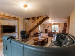 a living room with a leather couch and a staircase at Maison spacieuse près de Vesoul avec cheminée, idéale pour familles - FR-1-583-434 in Dampierre-sur-Linotte