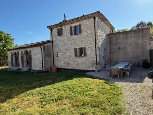 una casa in pietra con tavolo e sedie in cortile di Mas des sauges a Saint-Mathieu-de-Tréviers