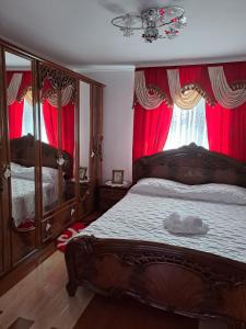a bedroom with a large wooden bed with red curtains at Pensiunea Floare de Bucovina in Frasin