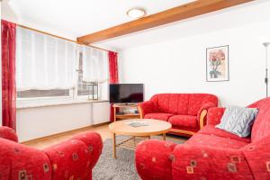 a living room with two red couches and a table at Haus Sonnenblume in Oldenswort