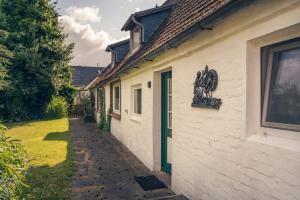 a white building with a green door next to a yard at Haus Sonnenblume in Oldenswort