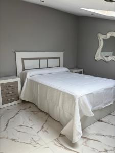a white bedroom with a large bed and marble floors at La pulga en el océano in Torrelavega
