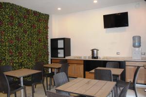 a dining room with tables and chairs and a tv at Hotel Leones in Puebla