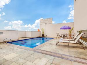 a patio with a pool and chairs and an umbrella at Flat Nações Unidas SP Limpeza Diária in São Paulo